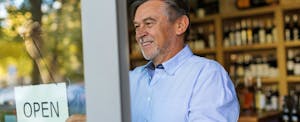 Man flipping the open sign over on his business' door, confident that he understands business credit scores