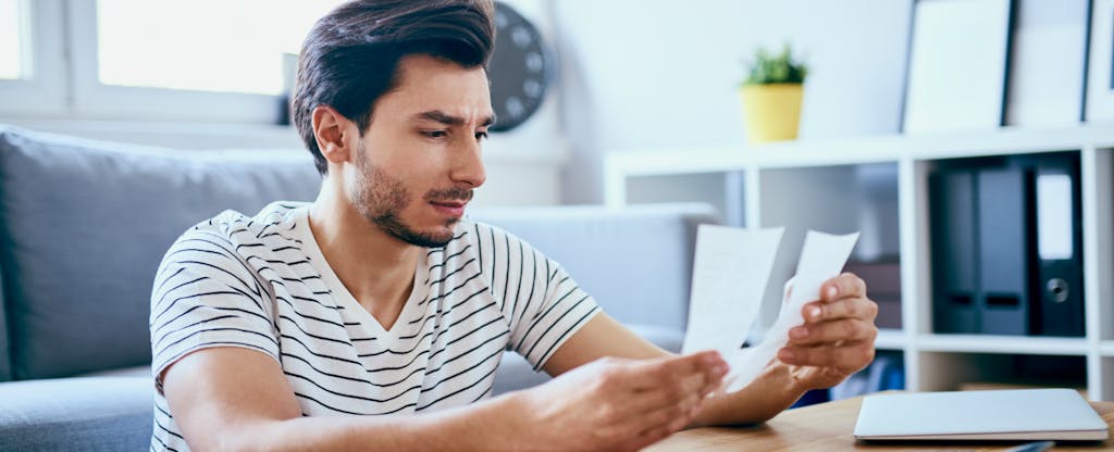 Man sitting on the floor reading about what you need to know about a credit card minimum payment