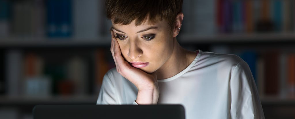 Young woman sitting in front of a glowing laptop and learning about how late payments can affect credit scores