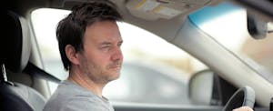 Man sits in his car, wondering how to get out of his upside down car loan Man sits in his car, wondering how to get out of his upside down car loan