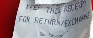 Crumpled Receipt Store receipt focusing on return policy on red background.