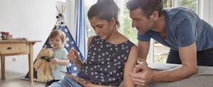 Couple using tablet at home with toddler son in background