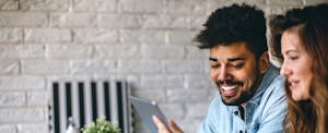 Young couple smiling and looking at tablet