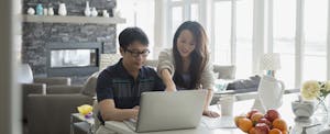 Father and daughter at laptop in kitchen