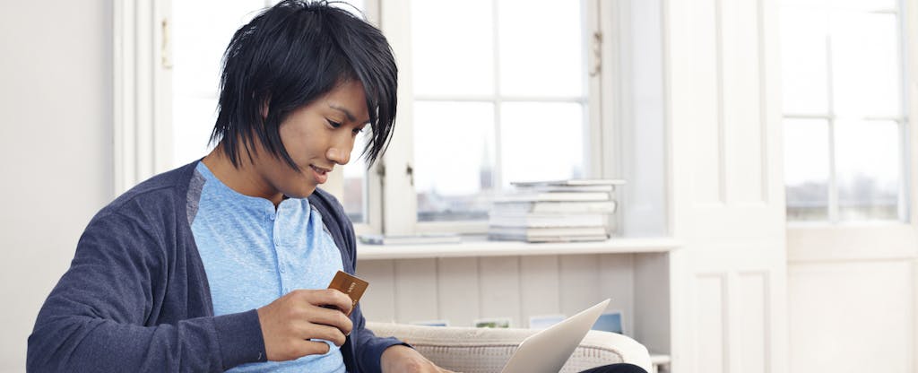 Young man using credit card and laptop
