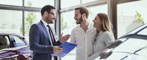 how-to-negotiate-car-price Couple buying a car from salesman.