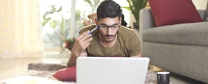 how-to-refinance-car-loan Young man drinking coffee and writing on document in living room