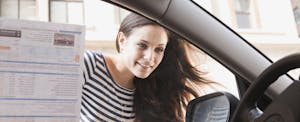 Woman looking into the window of a car with sale information on the window