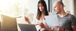 Couple sitting on sofa and wondering if they can get a car loan after bankruptcy
