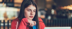 gen-z-driving-growth-credit-market College student sitting in a cafe, looking at her laptop and holding a credit card