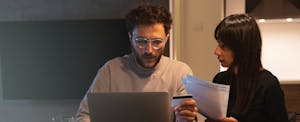 Young couple is sitting at the table with laptop and paying bills online
