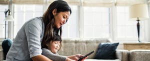 Mother with toddler daughter, looking up unemployment for self employed on her cellphone