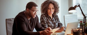 Man and woman sitting at desk with digital tablet, looking up what is home equity