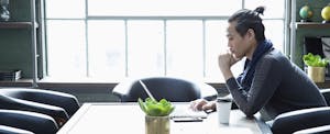 man in office with serious expression looking at laptop