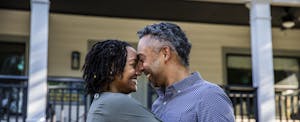 Smiling couple embraces in front of their new home.