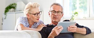 A couple preparing to sell their home review information on a tablet.
