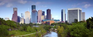houston-debt-statistics Late afternoon skyline of downtown Houston, Texas, with skyscrapers in the background with a blue sky behind, and a tree-lined river in the foreground