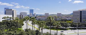 irvine-debt-statistics Aerial view of the downtown Irvine, California skyline with palm trees in the foreground and a blue sky overhead..