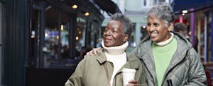 Two women outside on a city street, doing their holiday shopping together