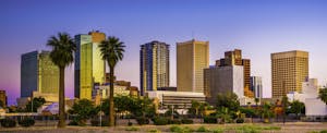 phoenix-debt-statistics Colorful sunset sky behind downtown Phoenix skyline, with palm trees in the foreground