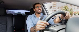 best-car-insurance-teachers Man smiling as he's driving his car