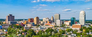 The downtown Winston-Salem, North Carolina, skyline under a cloudy blue sky.