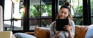 Woman sitting on her couch, reading on her tablet
