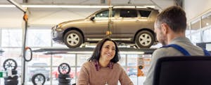 gravity-lending-auto-refinance-review-no-fee-refinancing Woman talks with salesperson at a car shop.