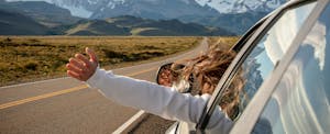turo-car-insurance-review Woman with arm out car window, driving to the mountains.