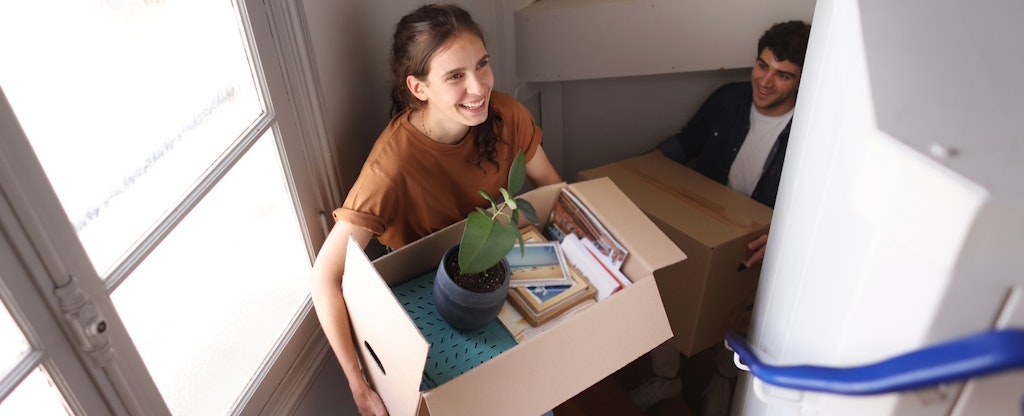 Young couple moving in to their new home and carrying boxes upstairs.