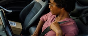 what-is-telematics-insurance Side view of responsible woman fastening a seatbelt before driving a car.