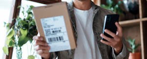 Man checking electronic banking on his smartphone as he received delivered packages from online purchases at home.